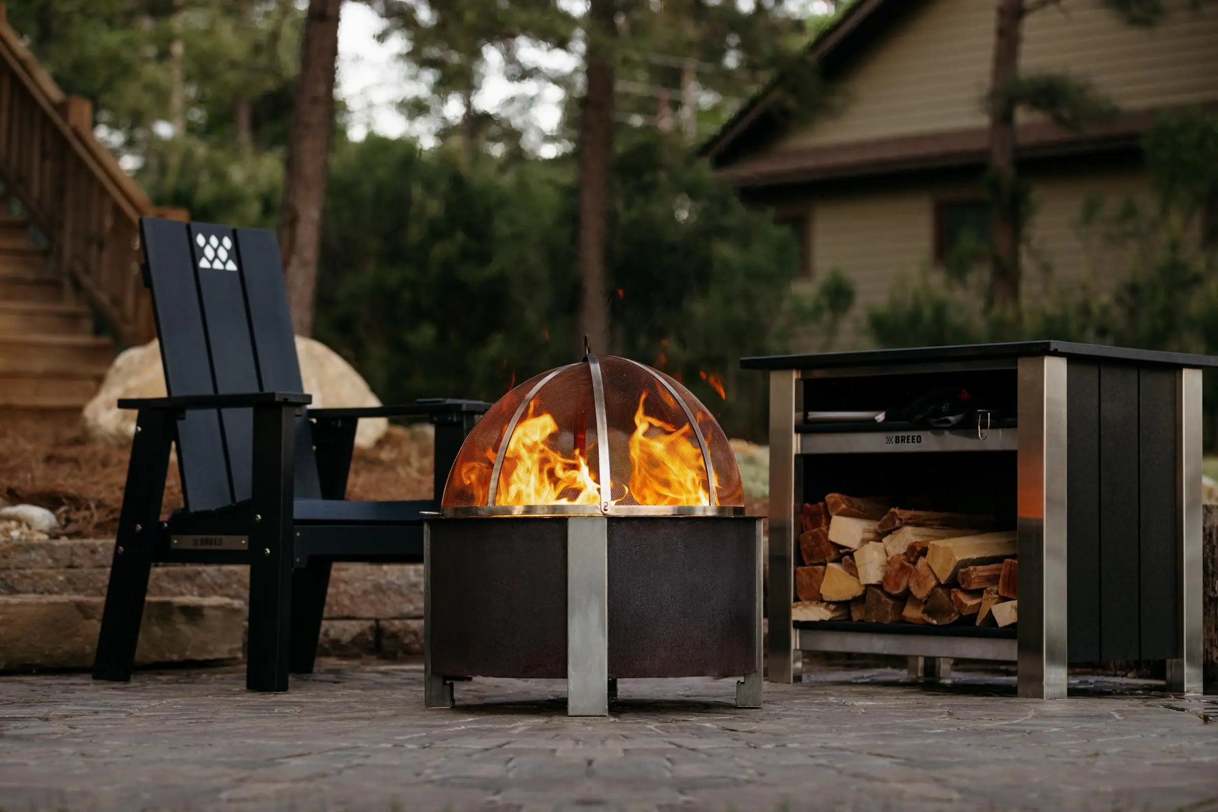 Breeo fire pit burning wood with a screen on top.