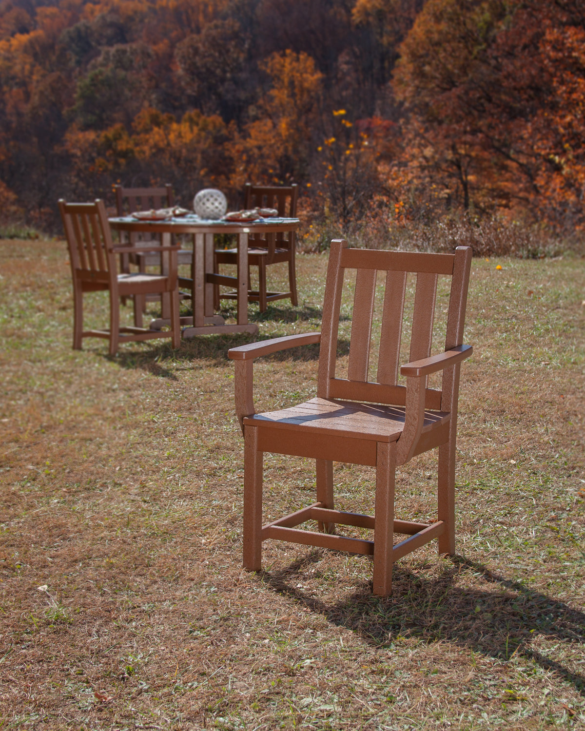 Lifestyle photo of the POLYWOOD Traditional Garden Dining Arm Chair in Teak