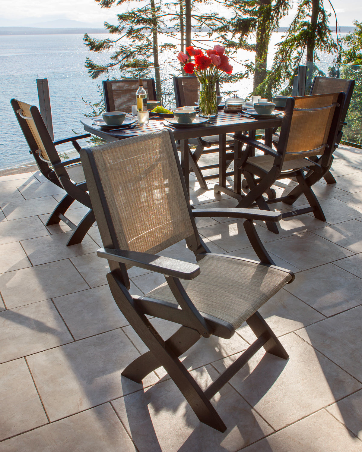 Mahogany POLYWOOD Coastal Folding Chairs with tan slings around a dining table on an ocean-view deck