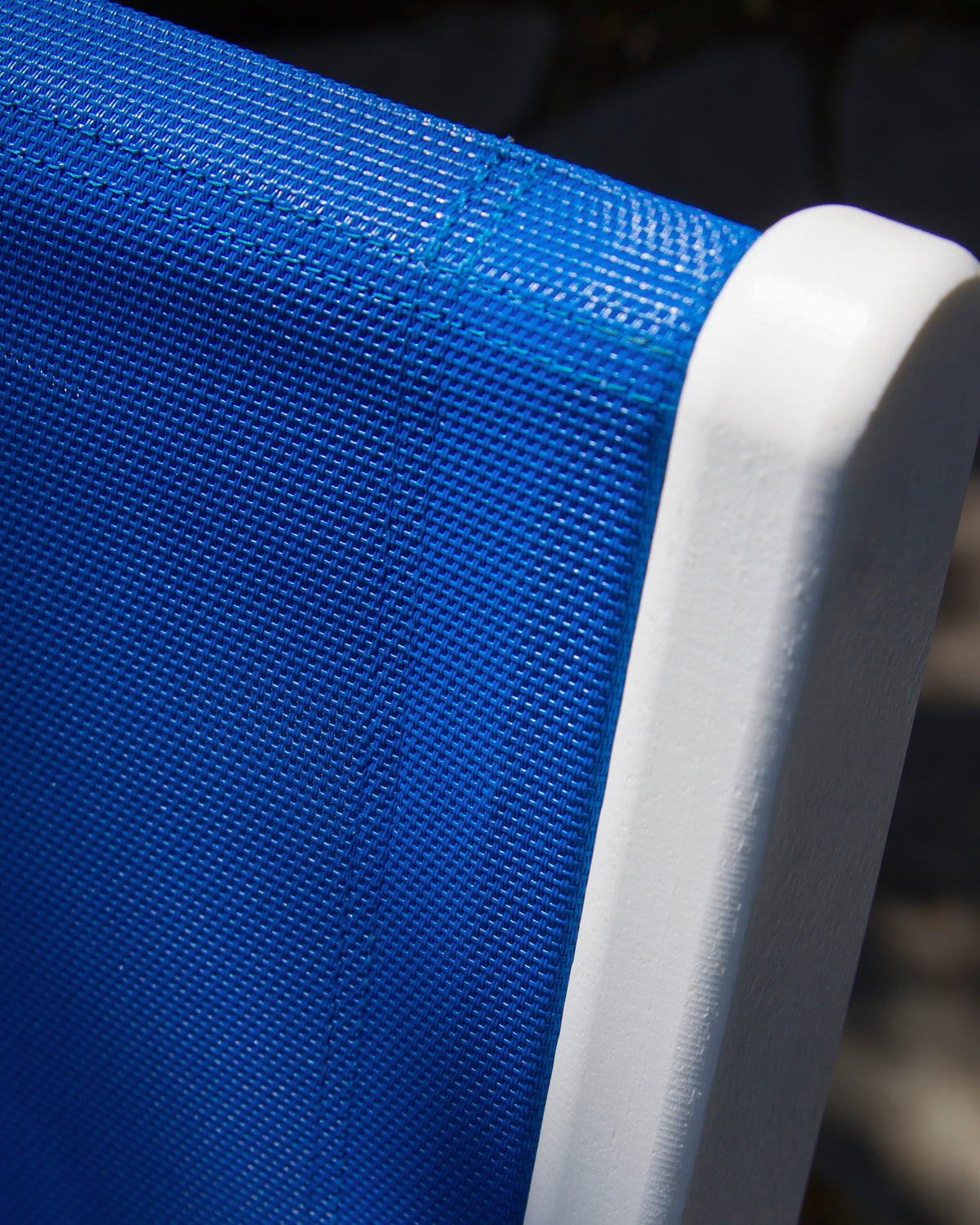 Close-up of a bright blue sling against the White POLYWOOD lumber frame