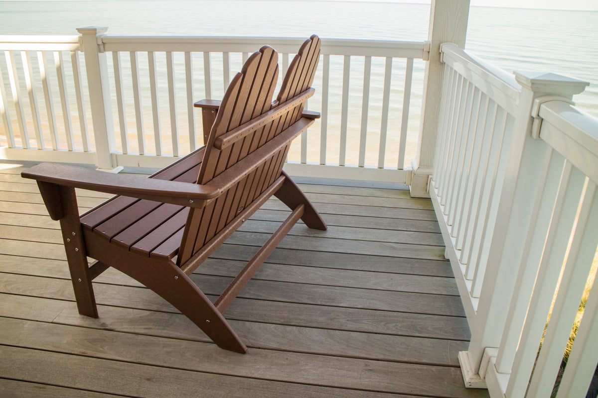 Side angle of the Teak POLYWOOD Vineyard 48" Adirondack Bench showing its reclined back on a porch