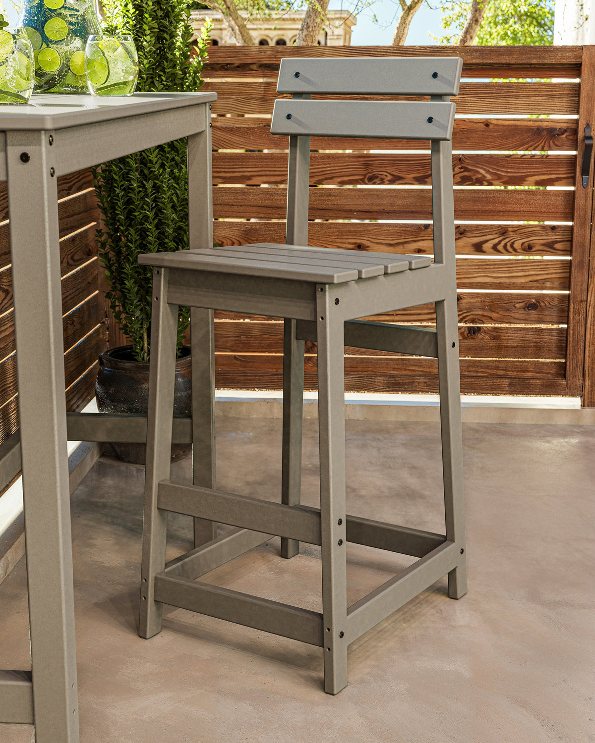 POLYWOOD Modern Studio Plaza Bar Chair in Slate Grey in an outdoor setting