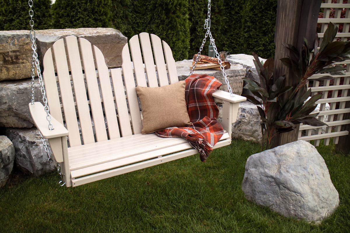 Sand POLYWOOD Vineyard Adirondack 48" Swing with a throw pillow and blanket hanging in a backyard
