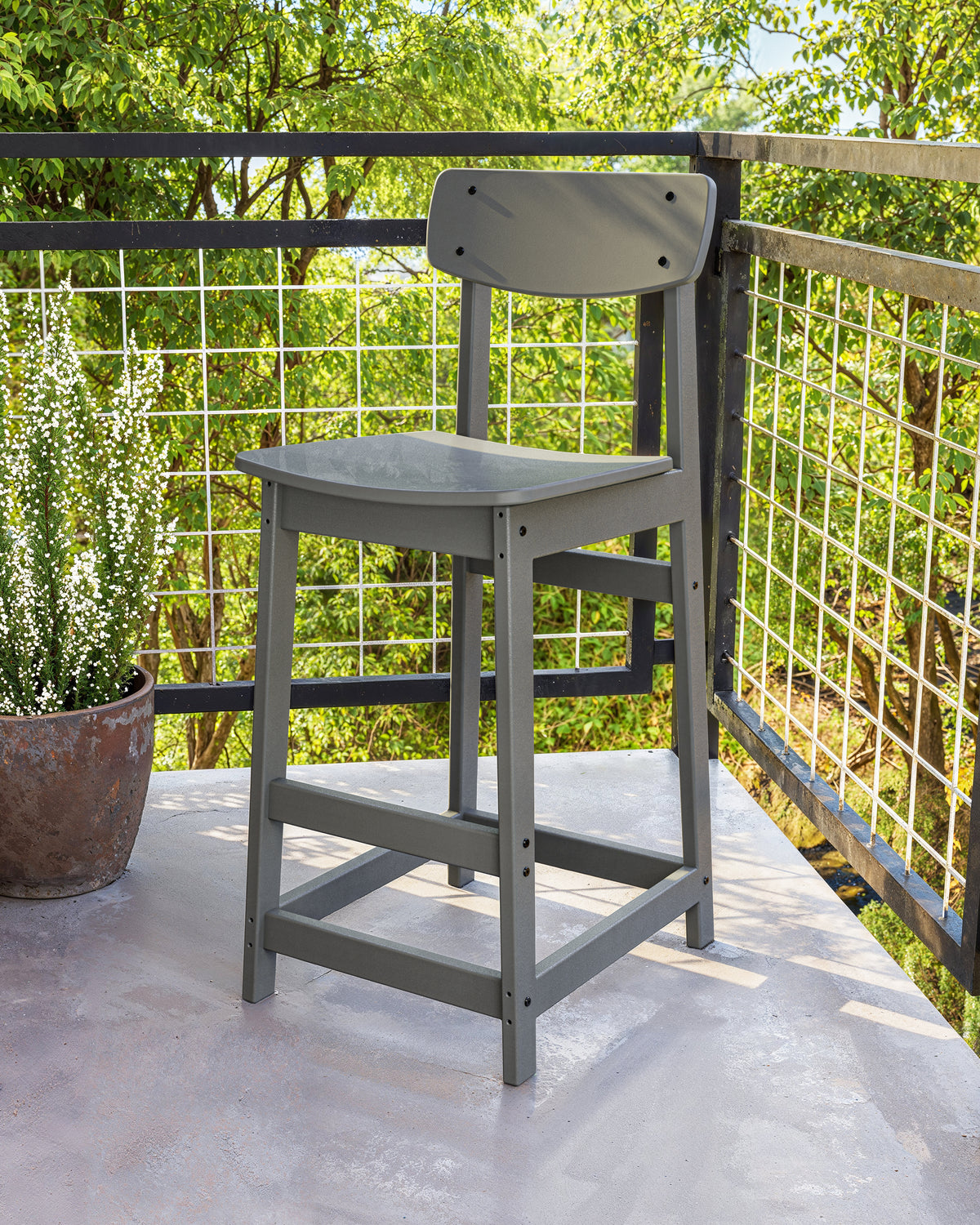 POLYWOOD Modern Studio Urban Bar Chair in Slate Grey in an outdoor setting