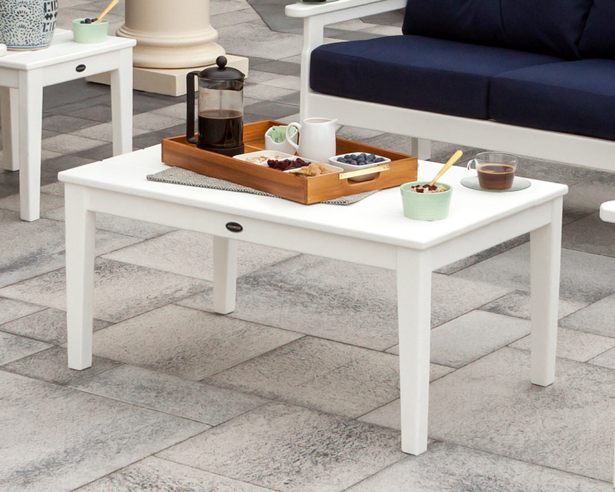 White POLYWOOD Newport 22" x 36" Coffee Table with a serving tray in front of a navy-cushioned outdoor sofa