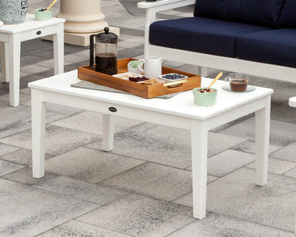 White POLYWOOD Newport 22" x 36" Coffee Table with a serving tray in front of a navy-cushioned outdoor sofa