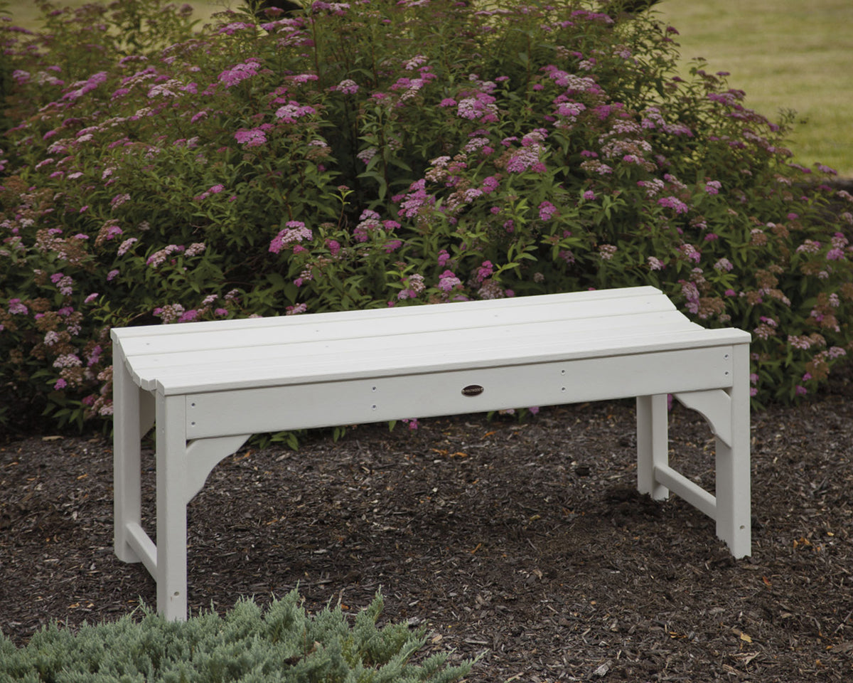 White POLYWOOD Traditional Garden 48" Backless Bench in a garden bed with pink flowering shrubs