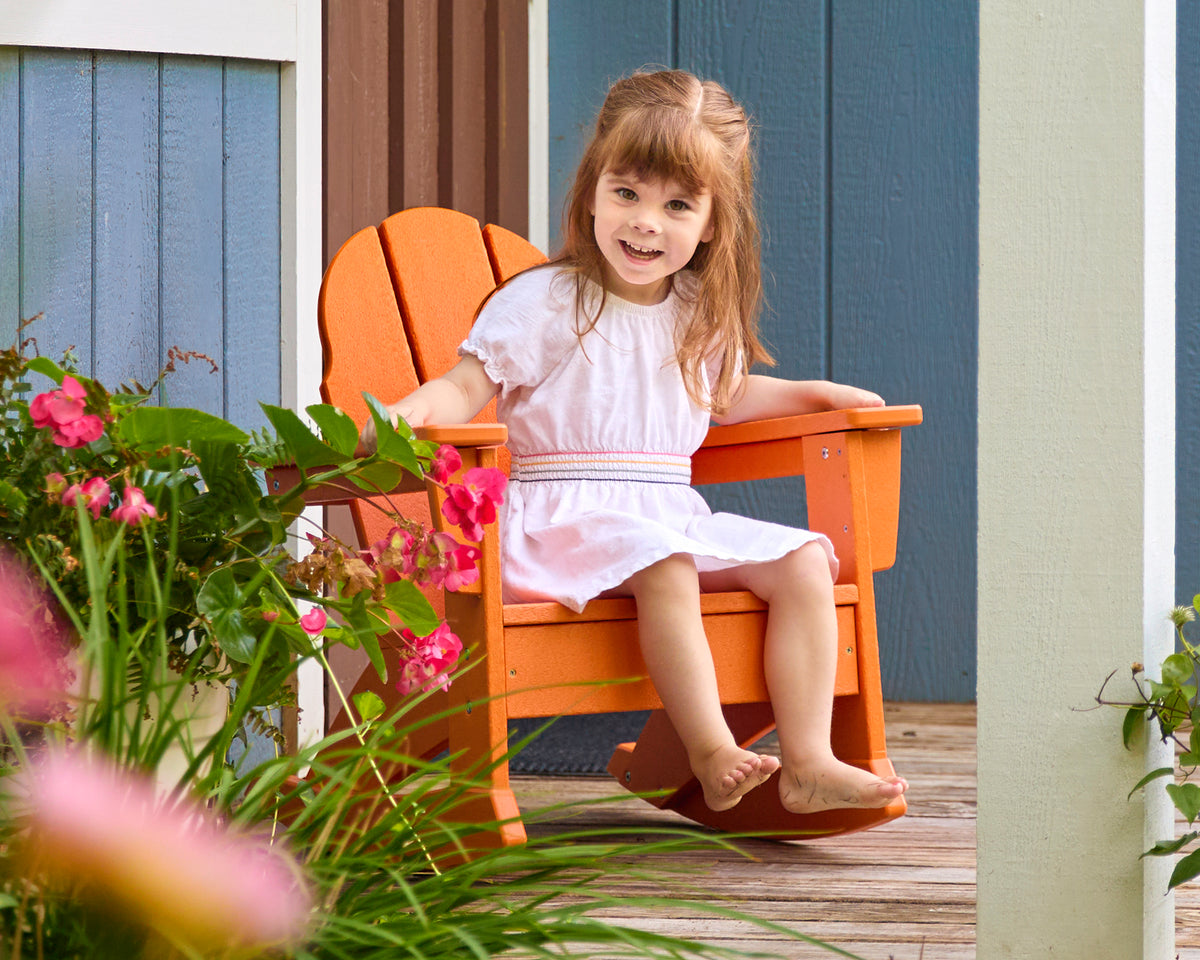 POLYWOOD Kids Vineyard Adirondack Rocking Chair in Tangerine in an outdoor setting