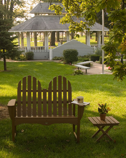 Teak POLYWOOD Classic Adirondack 48" Bench on a lawn next to a matching side table and gazebo