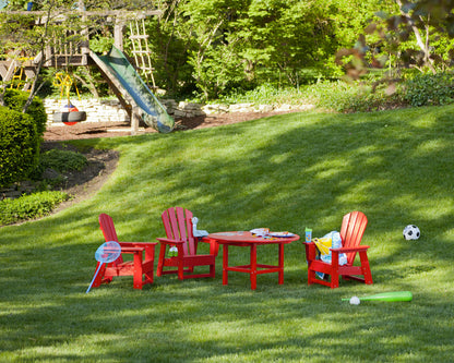 Lifestyle photo of the POLYWOOD Kids Adirondack Chair in Sunset Red
