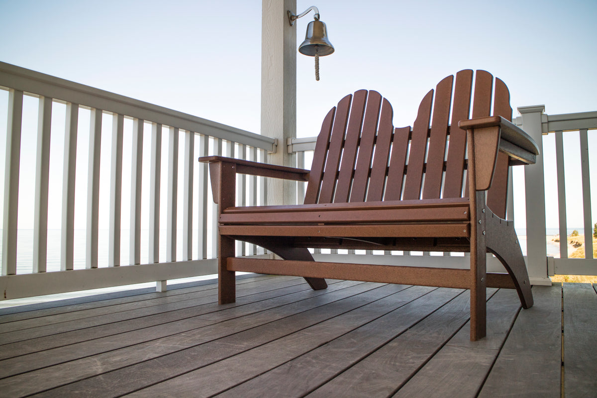 POLYWOOD Vineyard 48" Adirondack Bench in Teak on a lakeside porch beside a hanging bell