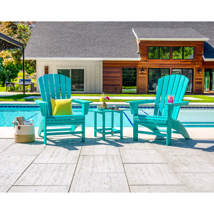 Two turquoise Adirondack chairs with a small table by a poolside, with a house in the background.