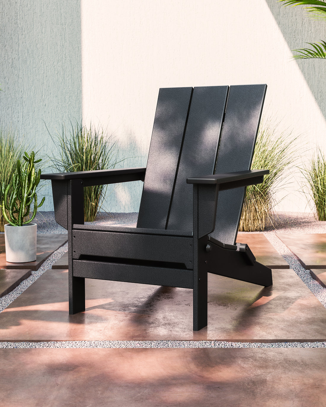 POLYWOOD Modern Studio Folding Adirondack Chair in Black in an outdoor setting