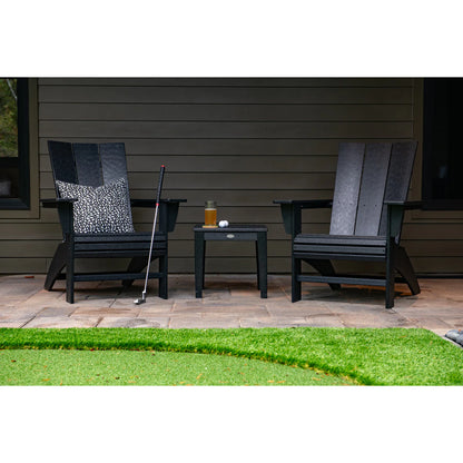 Two black Adirondack chairs with a small table on a patio.