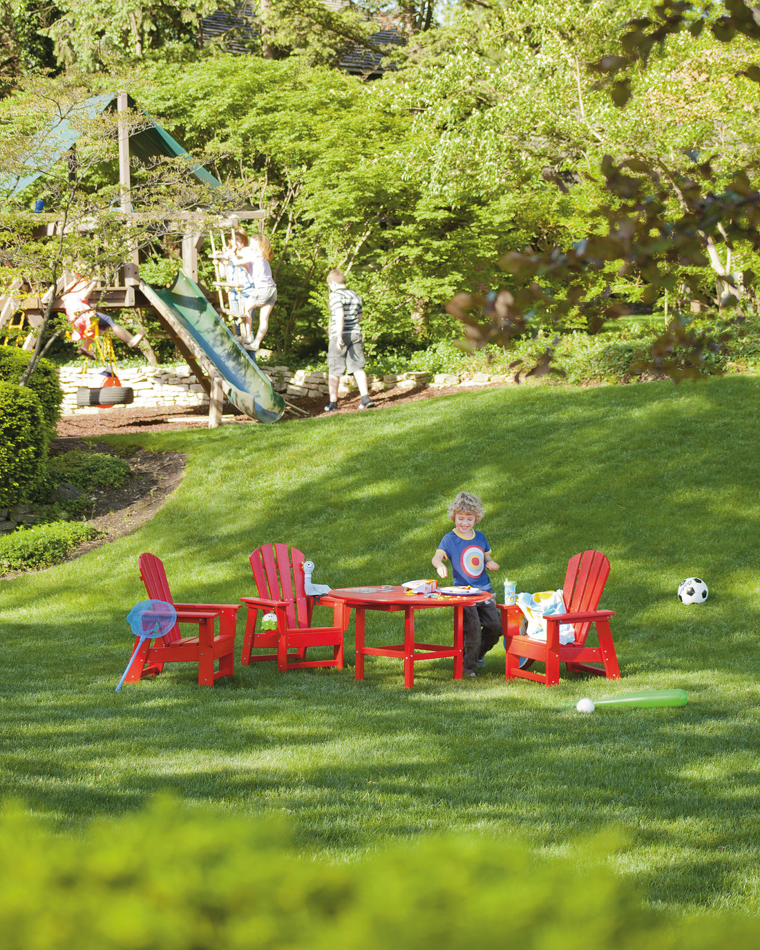 POLYWOOD Kids Adirondack Chair in Sunset Red in an outdoor setting